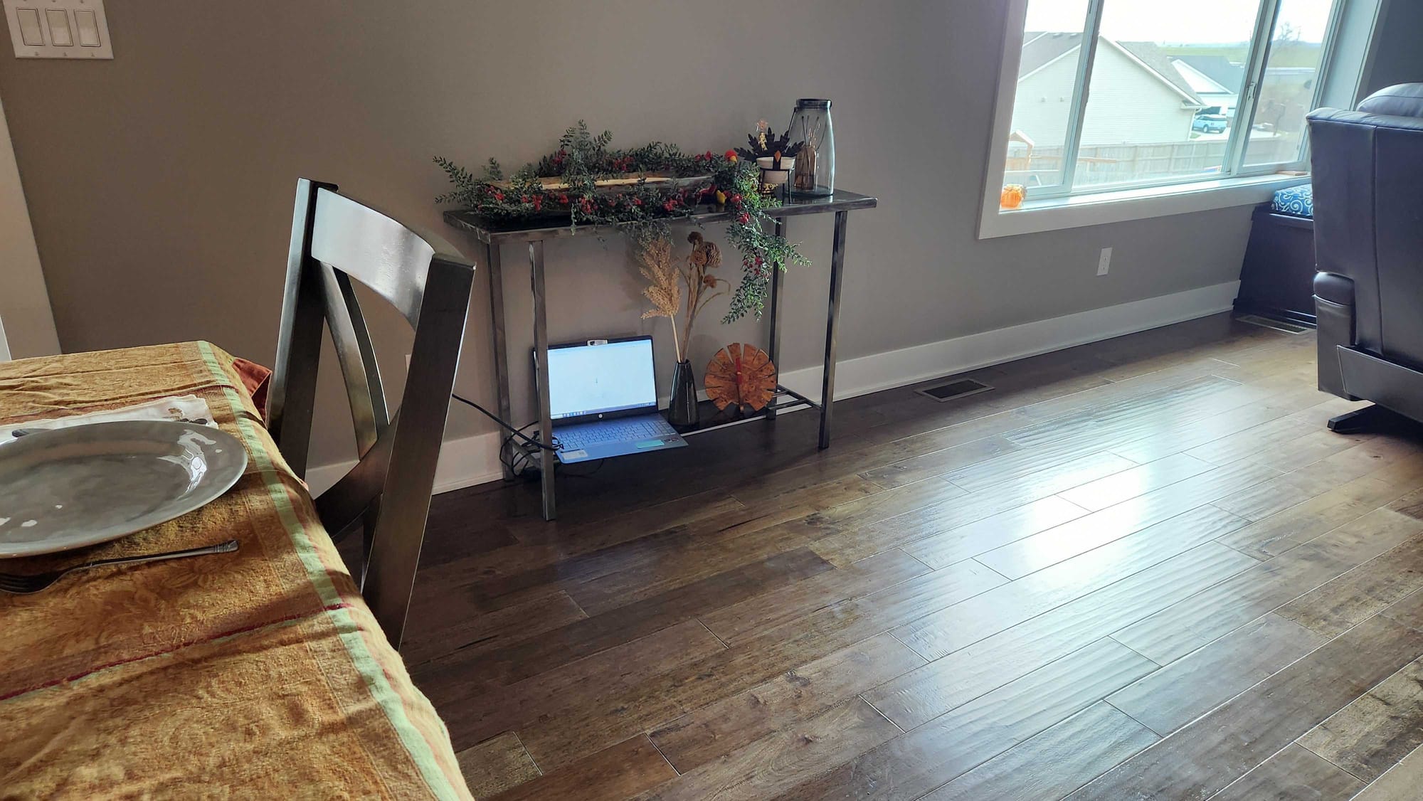 A picture of a living room decorated for thanksgiving with a laptop on the bottom of a small side table. The laptop has the AI powered thermometer app running, although you can't see it very well.